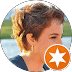 Person with short, light brown hair outdoors in San Antonio, facing left with a body of water and greenery in the background; a white star in an orange circle icon is overlaid at the bottom right—ideal for a Bankruptcy Lawyer profile.